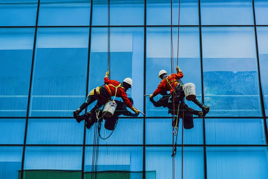 An adult male cleaning a glass window indoors, focusing on household chores and cleanliness.